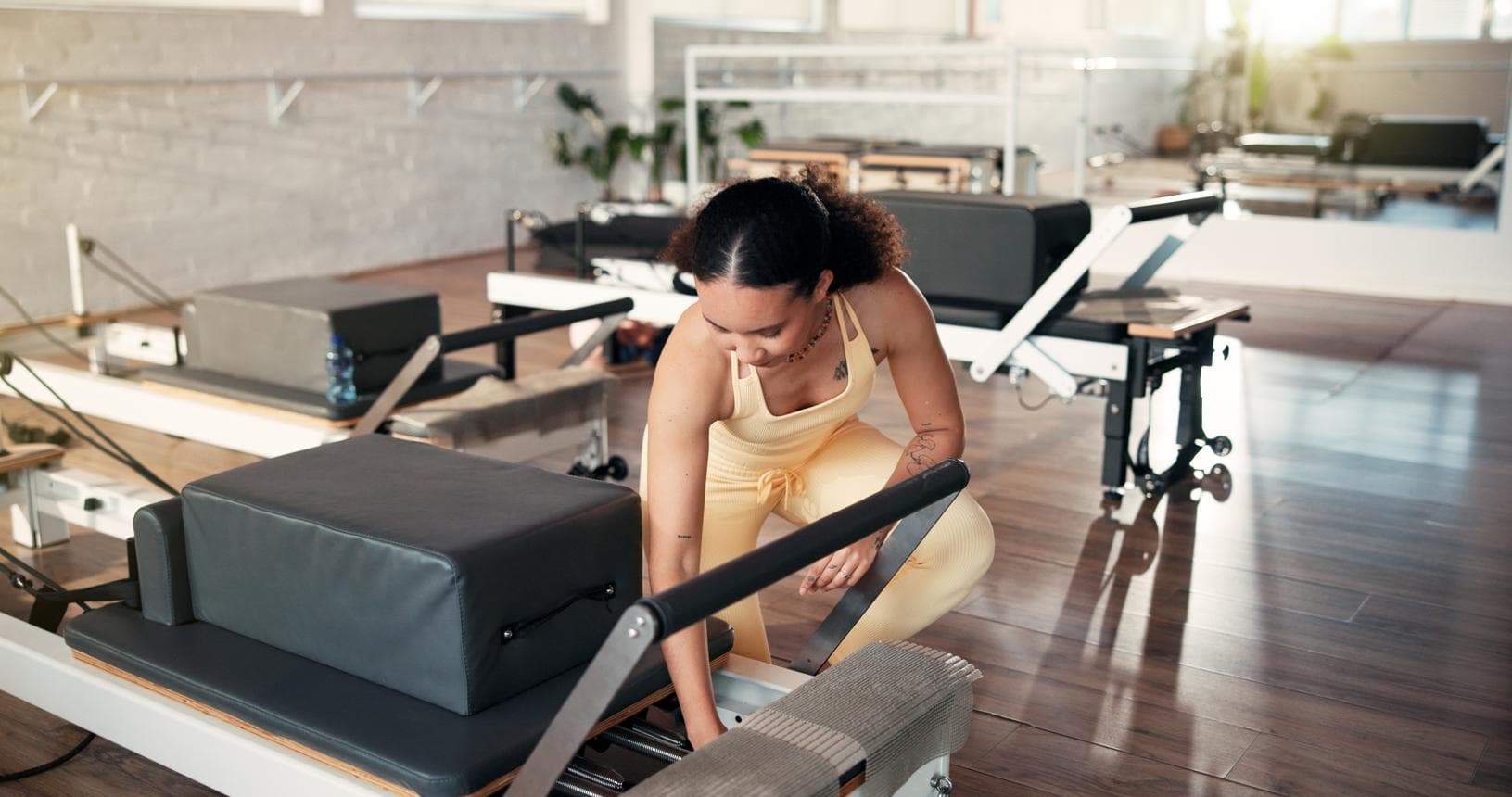 A studio team member attends to the carriage and fittings of a Reformer.